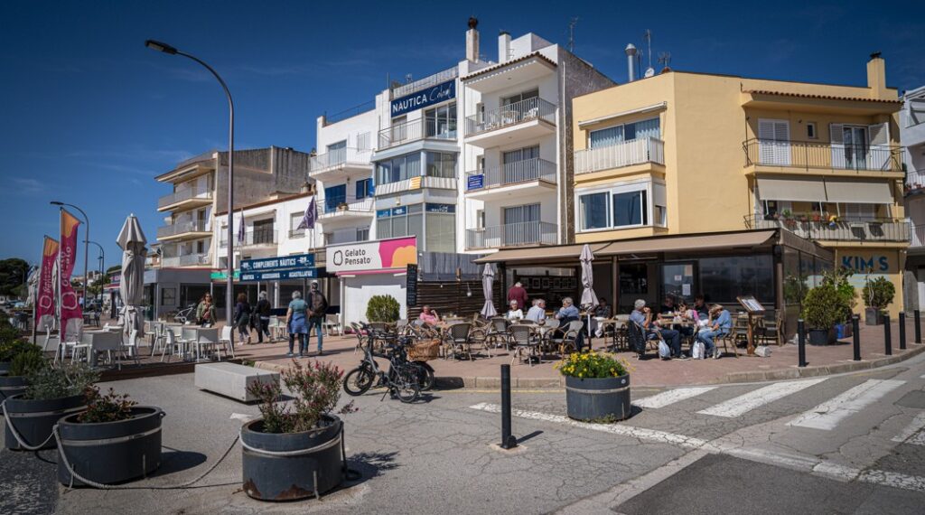 Un carrer de l'Estartit amb terrasses de bars i restaurants i elements comercials a la via pública